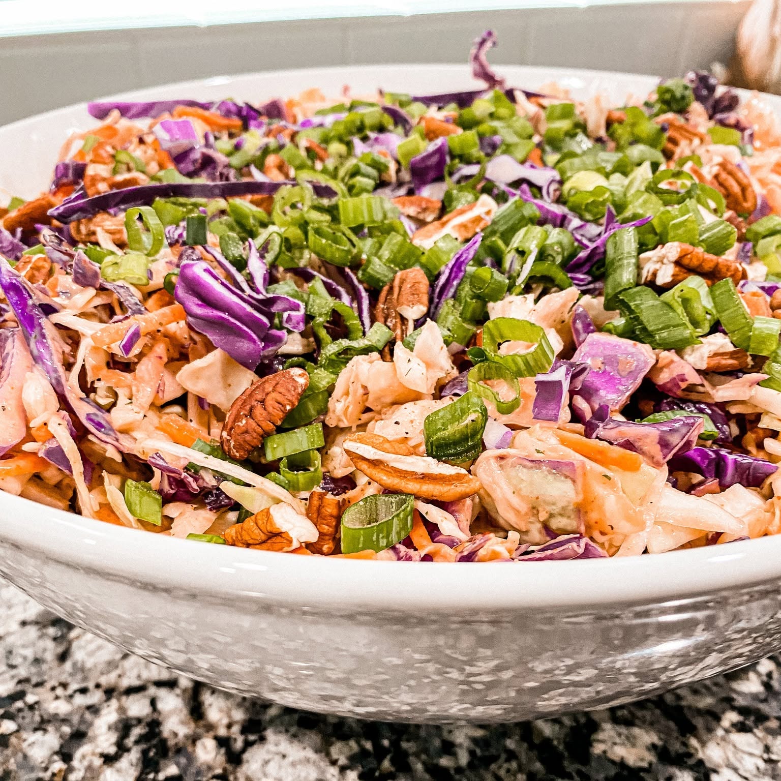 Colorful cabbage salad topped with green onions and pecans