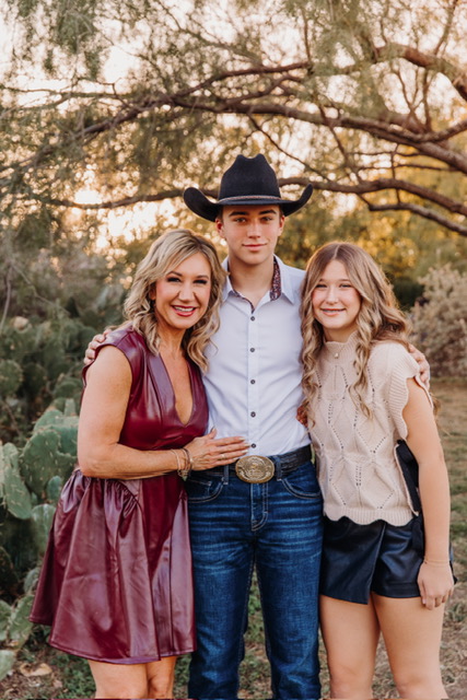 Family of three smiling together outdoors at sunset